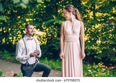 A young man stands on one knee in front of his beloved girl and makes her a proposal to become his wife
