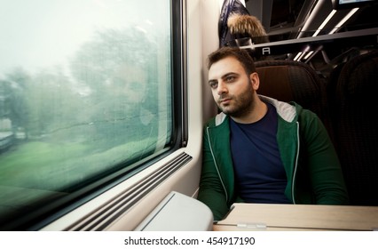 Young Man Staring Out The Train Window On A Rainy And Grey Day.