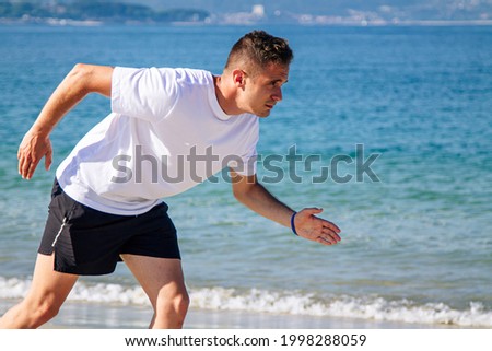 young man in starting position for jogging on the beach