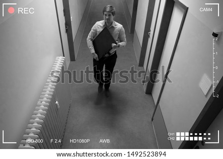 Young Man Stealing Computer Monitor Walking In Corridor Scene Through CCTV Camera