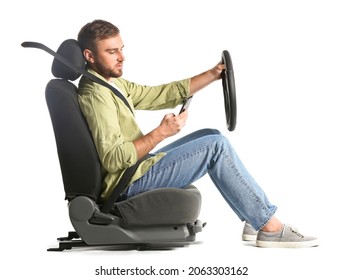 Young Man With Steering Wheel And Mobile Phone Sitting On Car Seat Against White Background