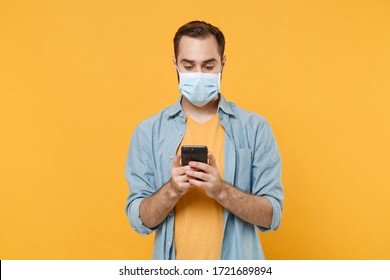 Young man in sterile face mask posing isolated on yellow background studio portrait. Epidemic pandemic coronavirus 2019-ncov sars covid-19 flu virus concept. Using mobile phone, typing sms message - Powered by Shutterstock