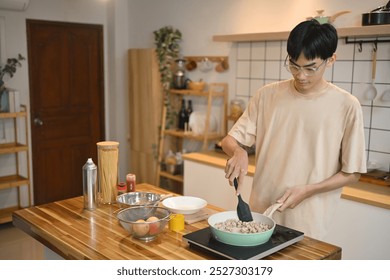 Young man stirring ingredients in a green pan with spatula. People, food and lifestyle concept - Powered by Shutterstock