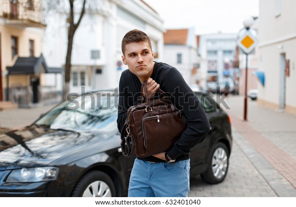 Young
man stole a leather bag on the background of a
car
