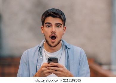 young man in the street with phone and expression of surprise - Shutterstock ID 2215199885