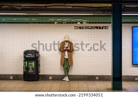 Young man with street style coat, hat, at the station on the New York Subway line without people
