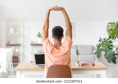Young man stretching his spine at home - Shutterstock ID 2112307511