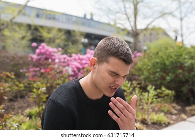 Young man struggling with allergies in the park on a bright spring day. - Powered by Shutterstock