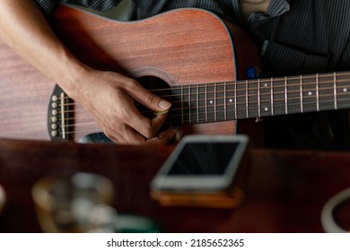 Young man strum his lover guitar At a small coffee shop in the countryside.