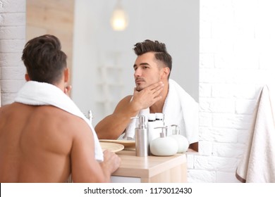 Young man with stubble ready for shaving near mirror in bathroom - Powered by Shutterstock