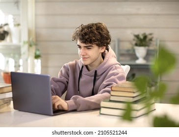 young man, student studying at home, looking at a laptop