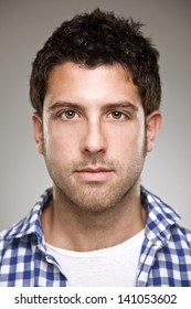 Young Man In Studio Looking At Camera/ Portrait Of A Normal Young Man On A Grey Background