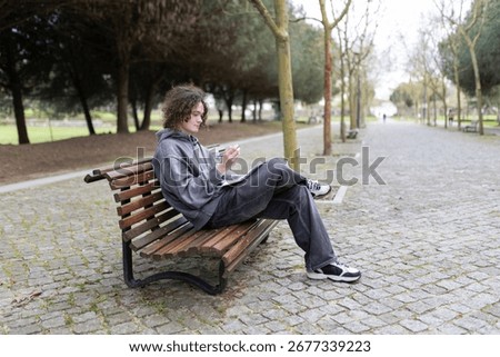 Young man studying and taking notes on a bench in a park