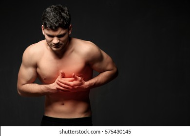 Young Man Suffering From Chest Pain On Black Background. Health Care Concept