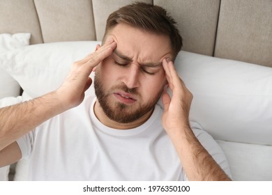 Young Man Suffering From Migraine In Bed, Above View