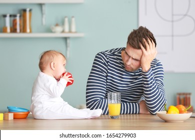 Young Man Suffering From Postnatal Depression In Kitchen