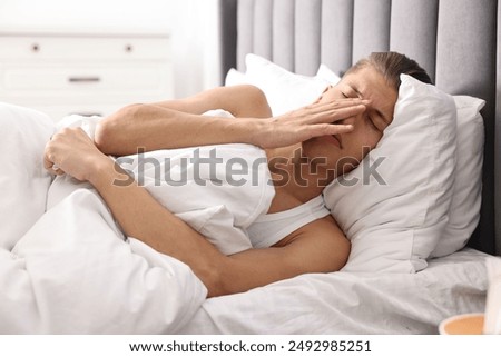 Young man suffering from sinusitis and lying in bed at home