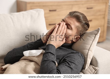 Young man suffering from sinusitis and lying in bed at home