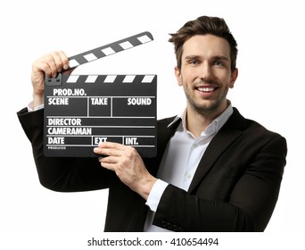 Young man in a suit holding a movie clapperboard, on white background