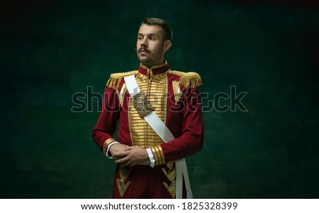 Young man in suit as Nicholas II isolated on dark green background. Retro style, comparison of eras concept. Beautiful male model like historical character, monarch, old-fashioned.