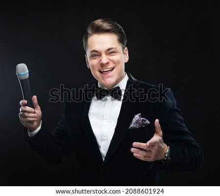 Young man in suit singing over the microphone with energy.