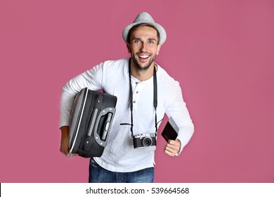Young Man With Suitcase, Camera And Ticket On Purple Background
