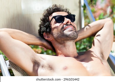 Young Man Sunbathing By Pool