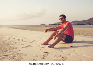 Young Man In Sunglasses Meets The Sunset On The Beach Near The Sea