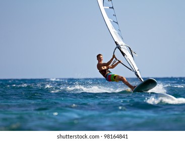 Young man surfing the wind on a bright summer day - Powered by Shutterstock