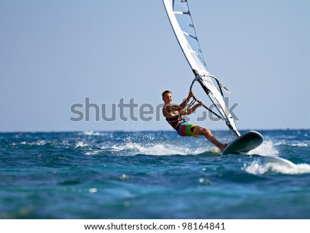 Young man surfing the wind on a bright summer day