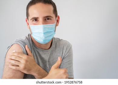 Young man with surgical mask and thumb up recently vaccinated with the Covid-19 vaccine - Powered by Shutterstock