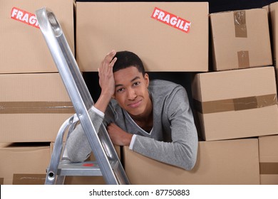 Young Man Surrounded By Boxes Moving Into A New Apartment