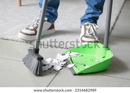 Young man sweeping floor with broom at home, closeup