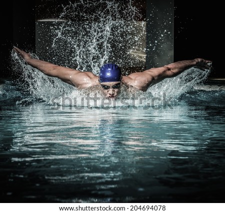 Young man in swimming cap and goggles swim using breaststroke technique 