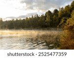 The young man swimming in the river. Misty sunrise over a lake. A foggy morning on autumn by a small lake. Misty reflection in water. Dreamy wanderlust