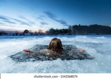 Young man swims in the winter lake