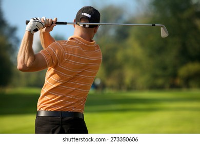 Young Man Swinging Golf Club, Rear View