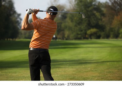 Young Man Swinging Golf Club, Rear View