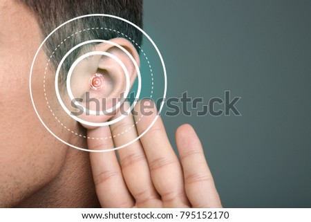 Young man with symptom of hearing loss on color background