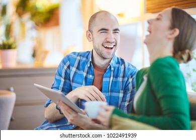 Young Man With Tablet And His Girlfriend Laughing While Watching Movie Or Series Online