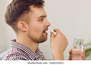 Young Man Takes Medication Prescribed By His Physician. Side Profile Closeup View Of A Happy Handsome Caucasian Man Taking A Pill And Drinking A Glass Of Water. Health, Medicine, Treatment Concept