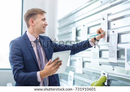A young man takes notes at the office. A big plan.