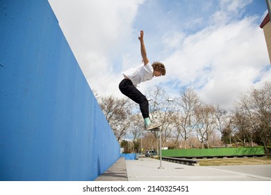 Young Man Taking A Big Leap From A Wall In The Street