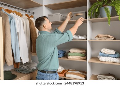 Young man taking box from shelf in walk-in closet - Powered by Shutterstock