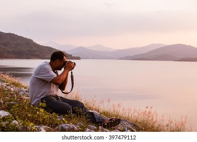 young man taking camera at dam in the evening