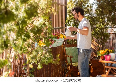 Young man taking care of his plants on the balcony
