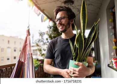 Young man taking care of his plants on a balcony
