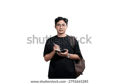 Young Man Taking Notes in Notebook While Wearing Backpack