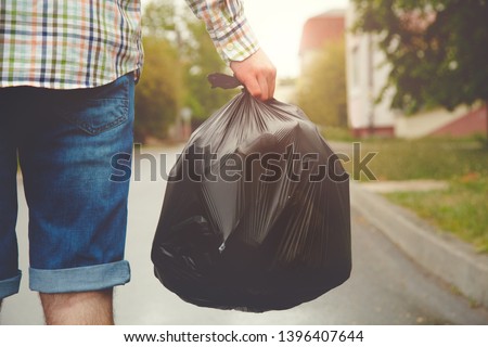 young man taking out garbage in black plastic bag