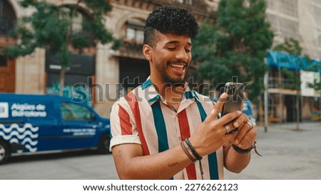 Young man taking photo on cellphone on summer day outdoors